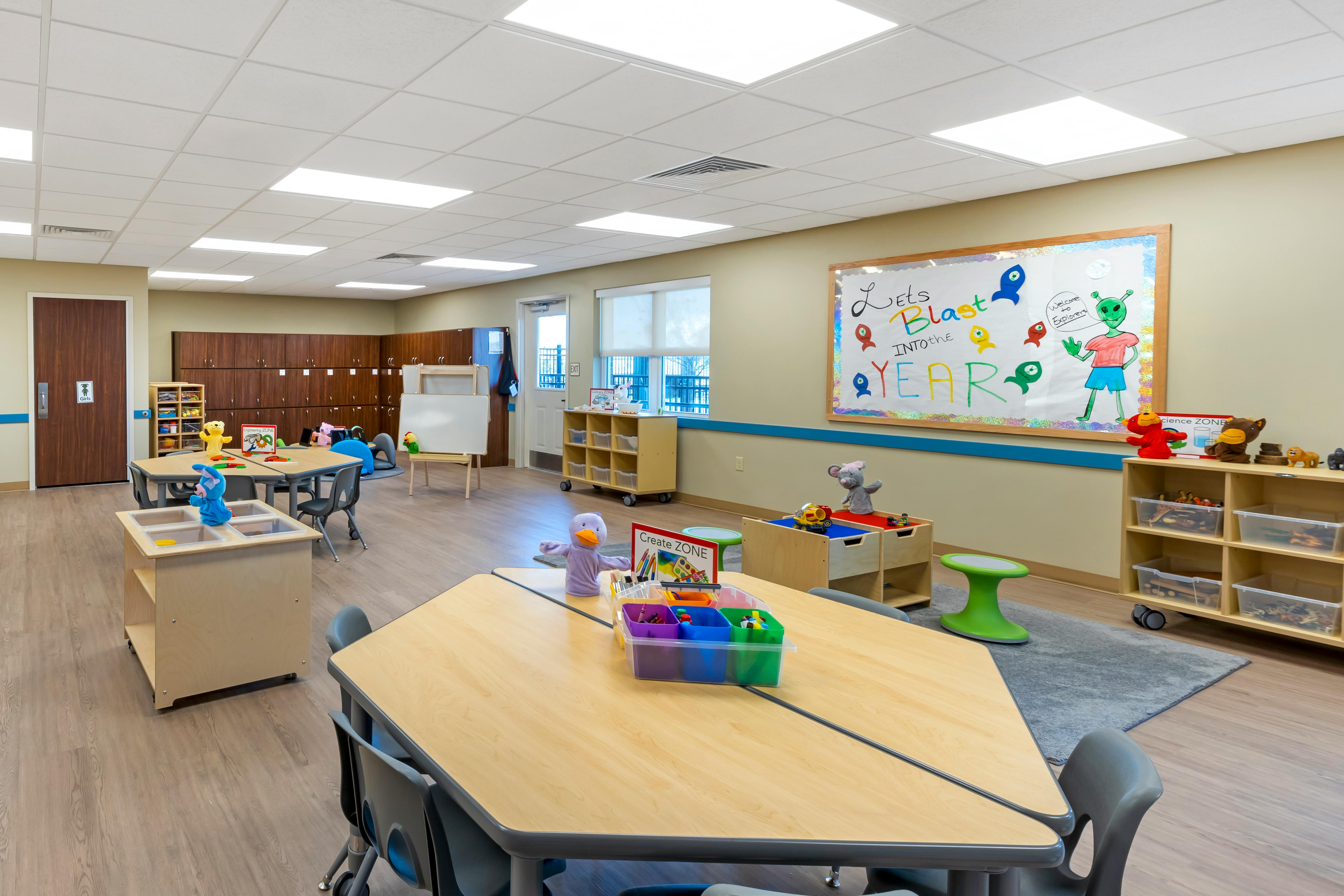 Classroom with tables, chairs, lockers, and a bulletin board saying "Let's Blast Into The Year"