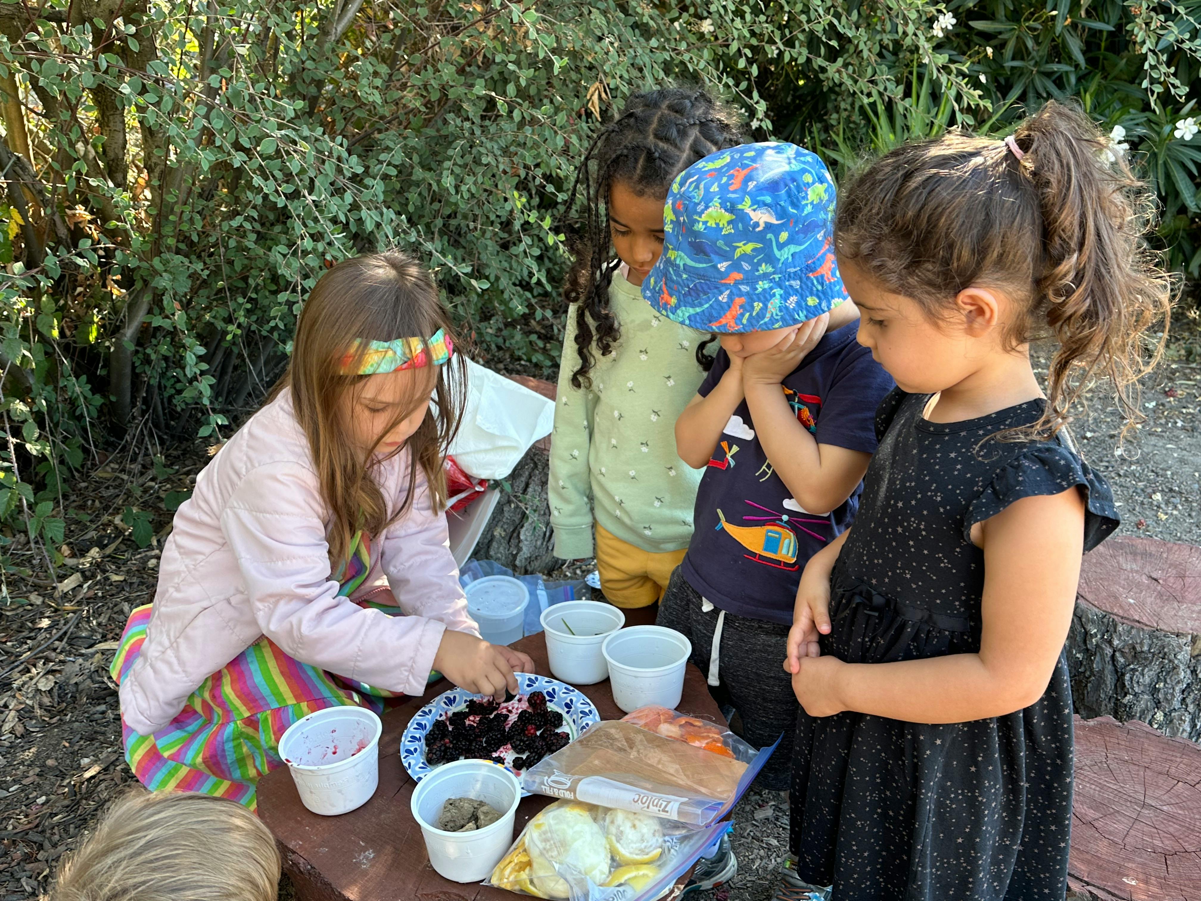 Four children gathered around a table with food and cups