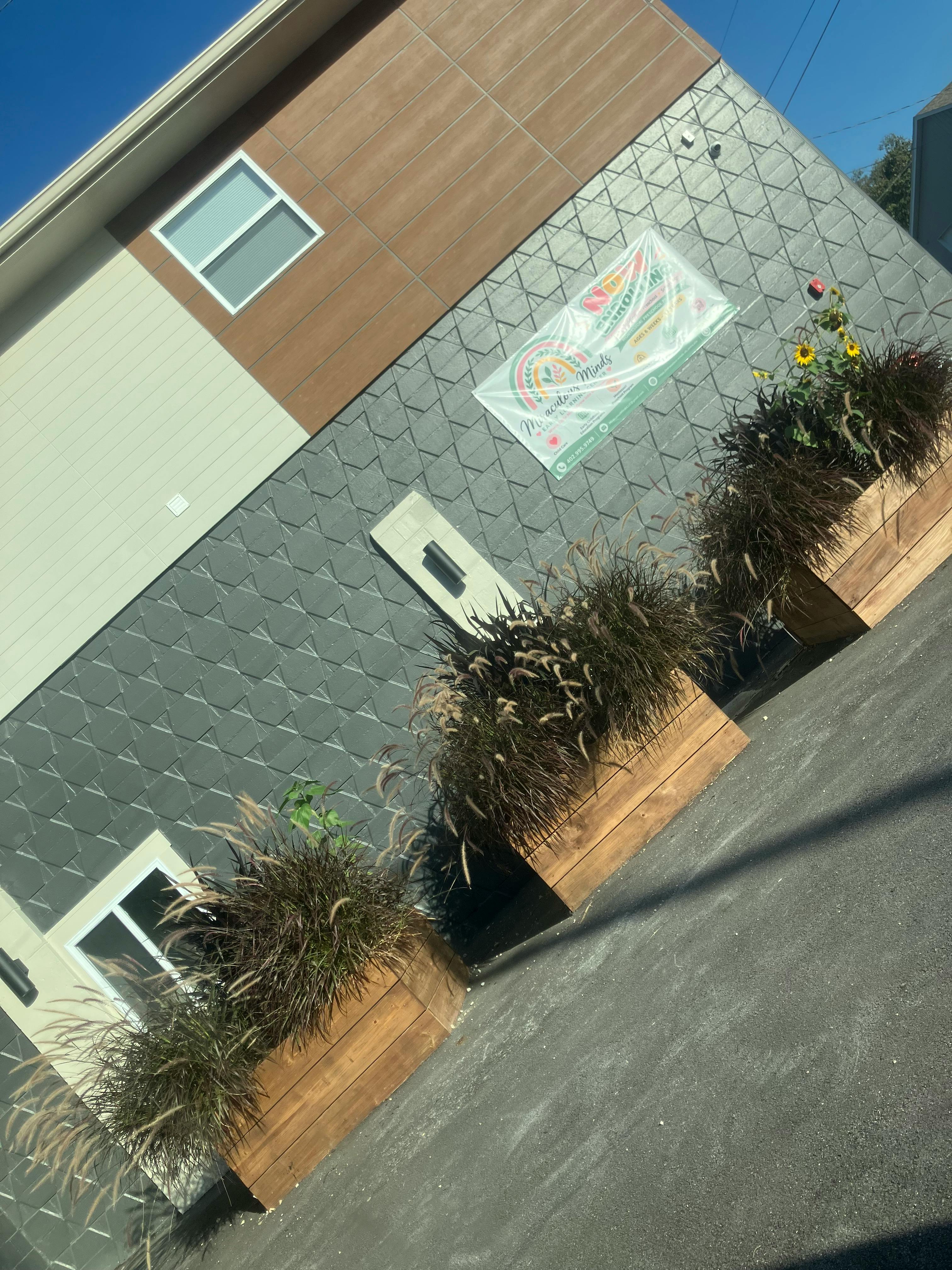 Exterior wall of a building with rectangular wooden planters and a banner