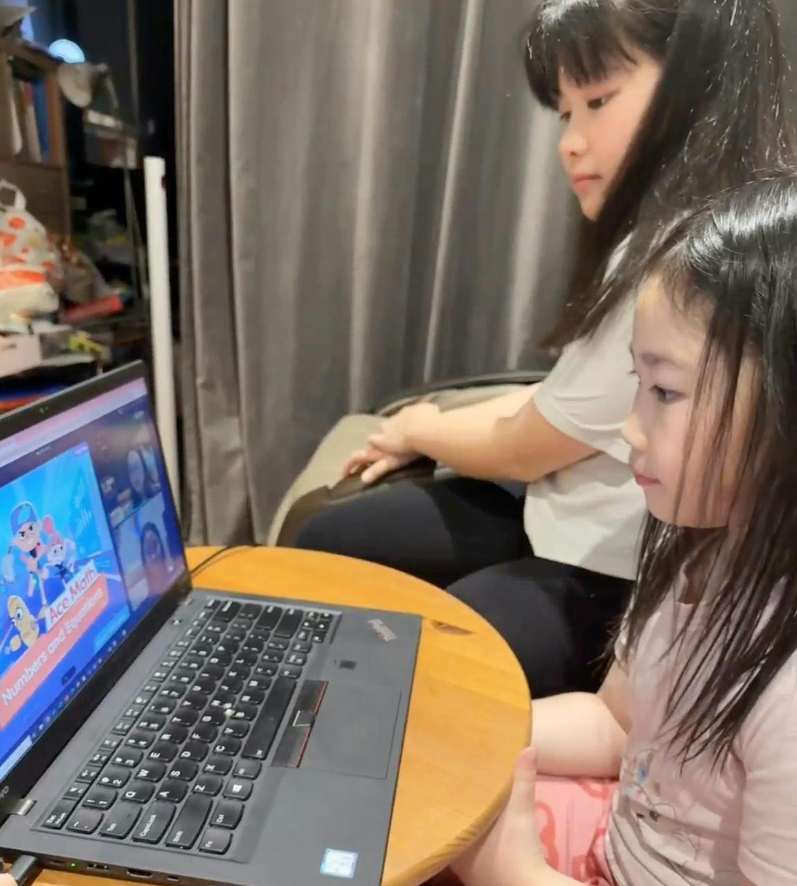 Two children sitting and watching an online Ace Math lesson on a laptop