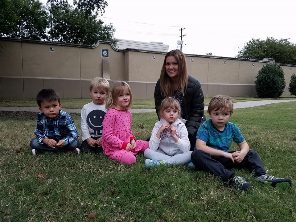 Adult and four children sitting on grass
