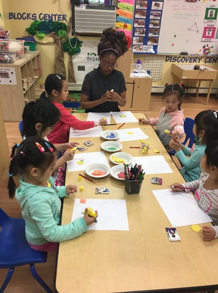 Person and children sitting at a table with art supplies