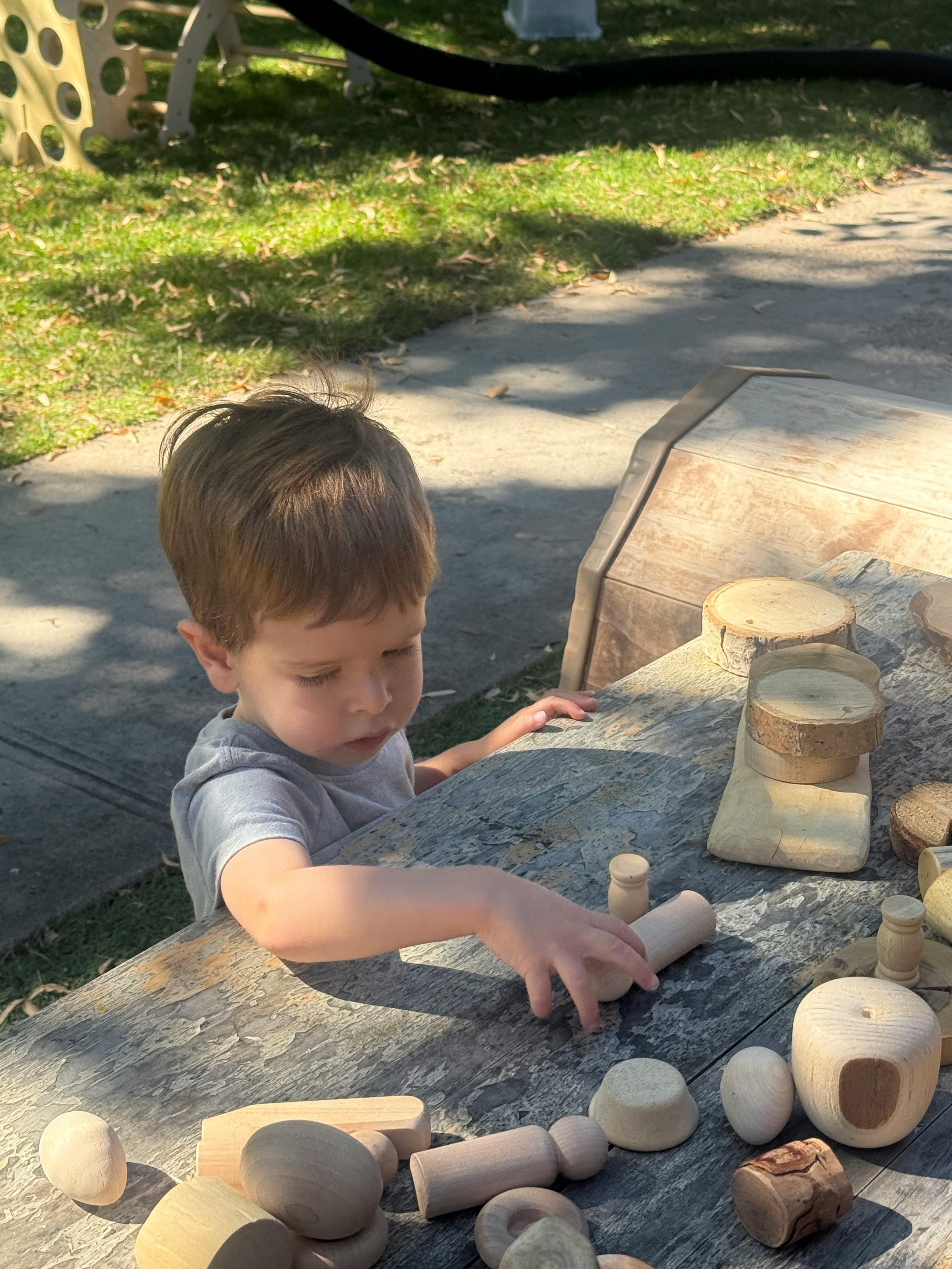 Child playing with wooden blocks on a stone surface