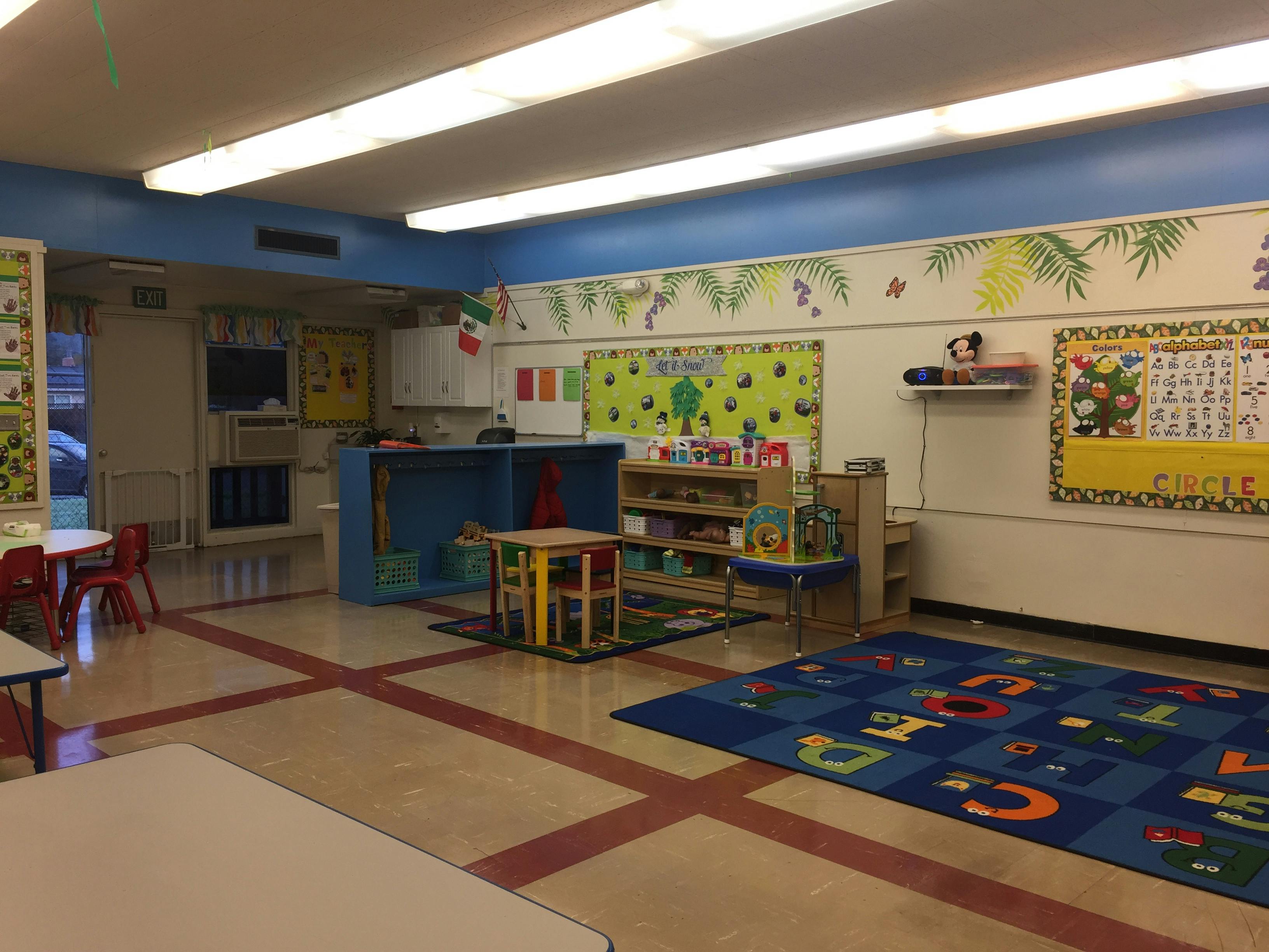 Classroom with small tables, chairs, and a colorful alphabet rug