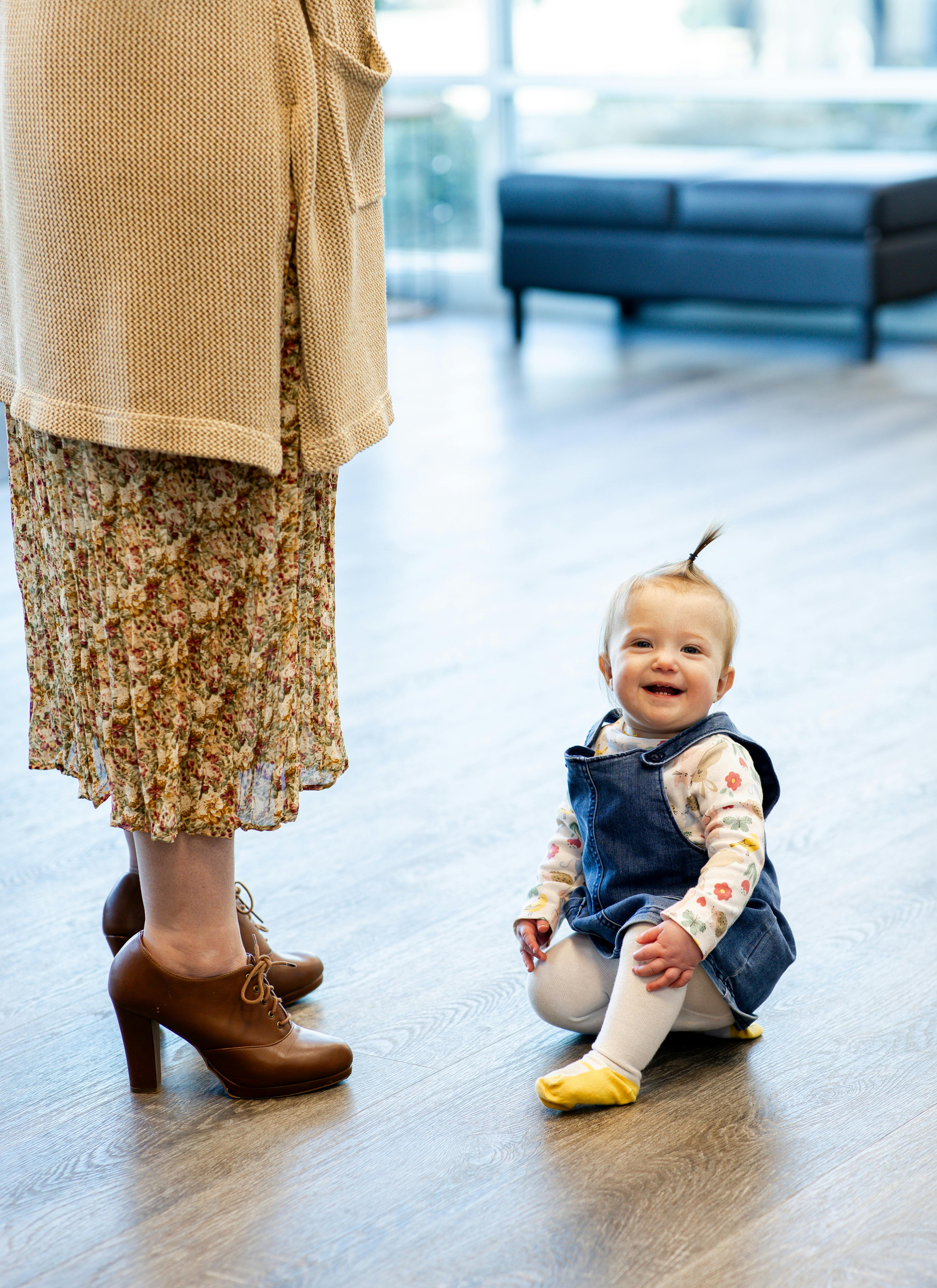 Child sitting on the floor next to an adult's legs
