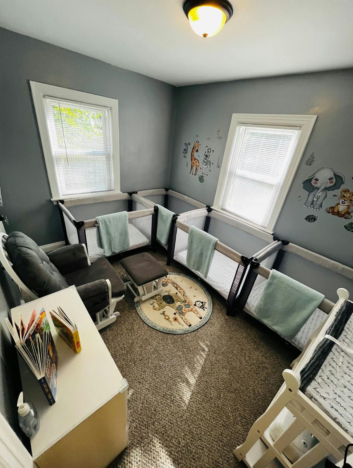 Nursery room with multiple cribs, a rocking chair, and a small table