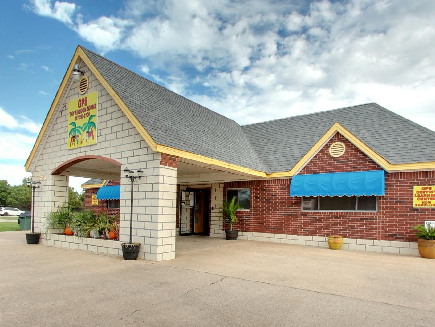 Building with brick and stone facade, blue awnings, and a sign on the gable