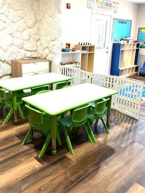 Two green tables with chairs in a classroom