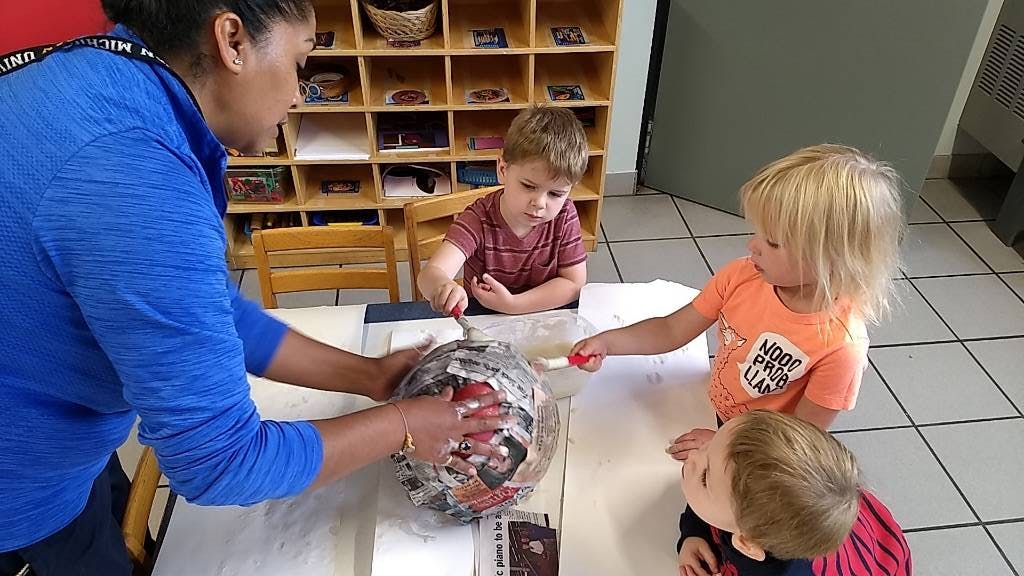 Adult and three children working on a craft project at a table