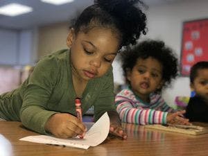 Child drawing on paper with a crayon