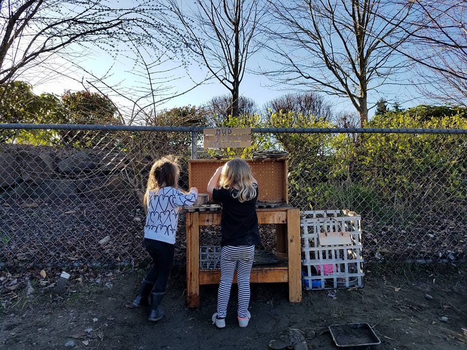 Two children playing at a wooden outdoor activity station
