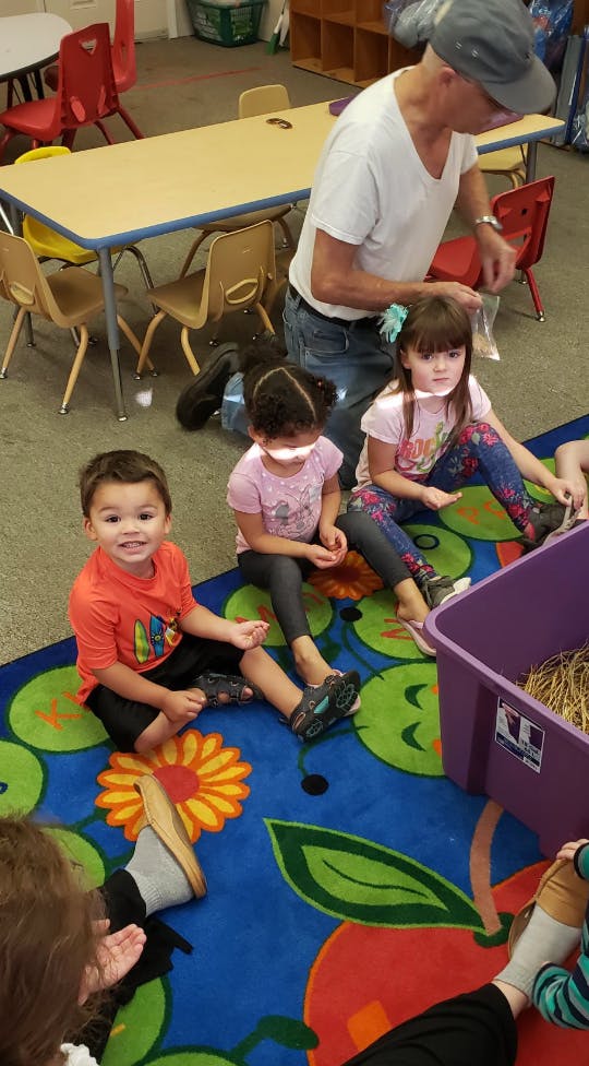 Adult interacting with children on a colorful rug