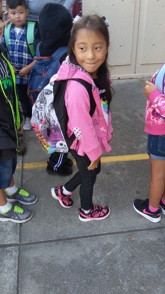 Child with backpack walking among other children