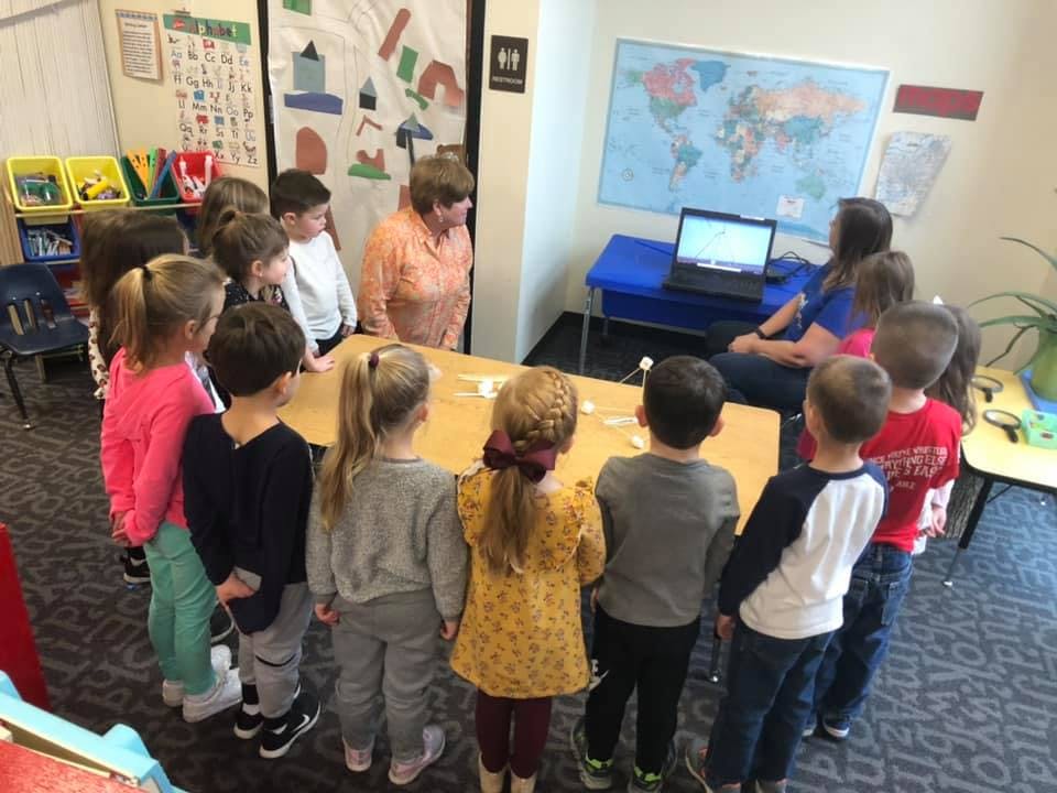Adults and children gathered around a table in a classroom