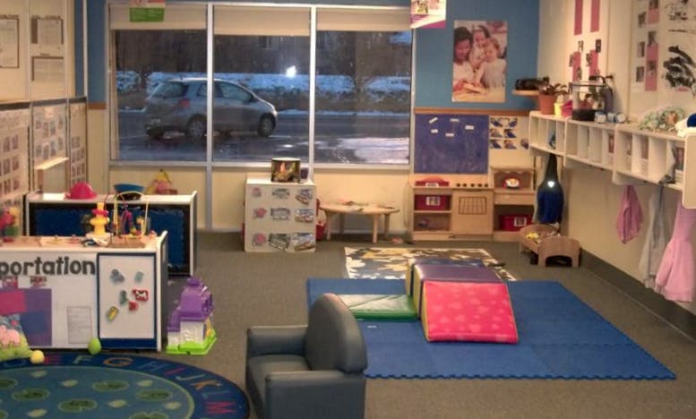An empty childcare classroom with play areas and a street visible through large windows
