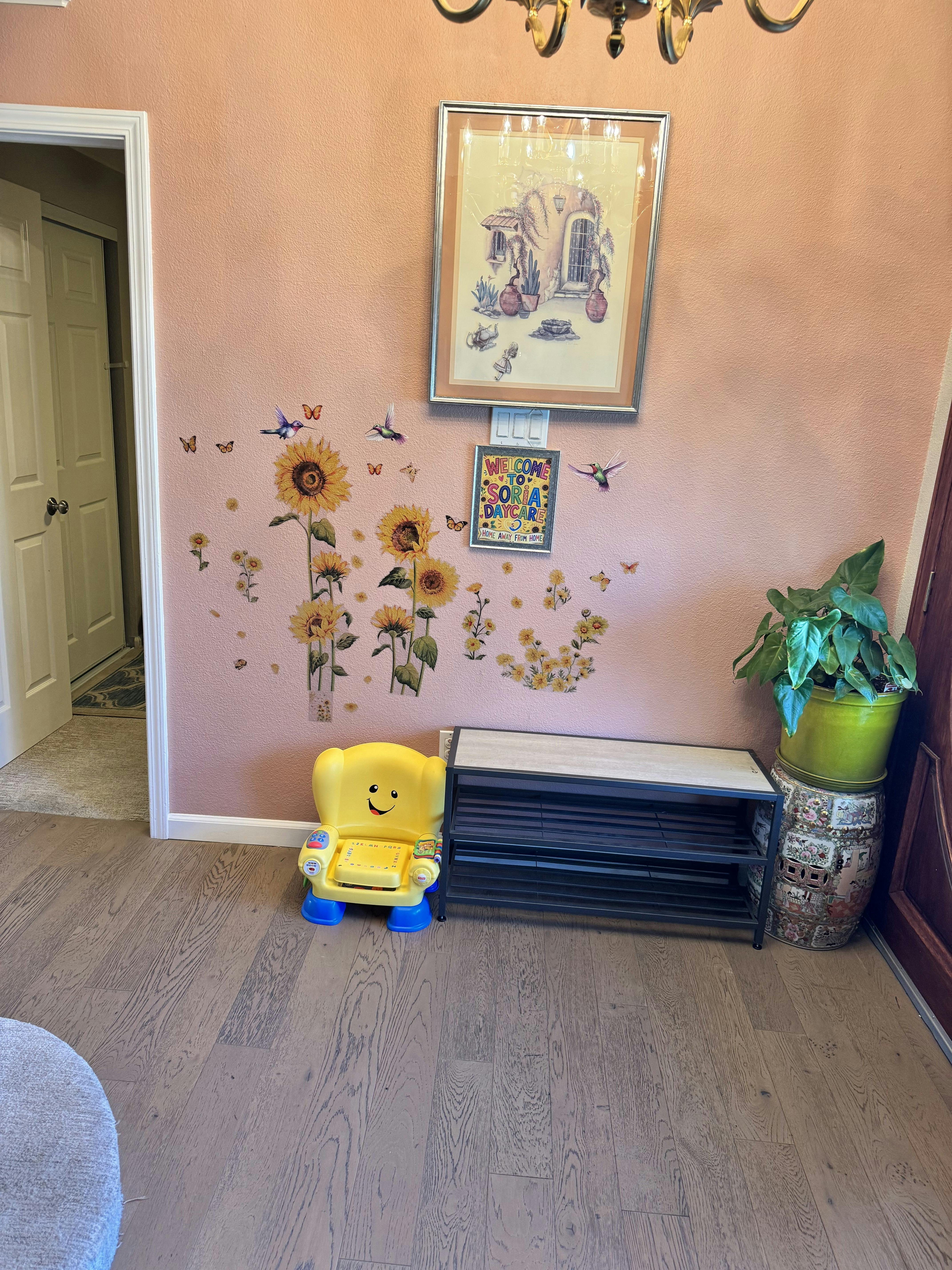 Small yellow chair and shoe rack under sunflower wall decals and daycare sign