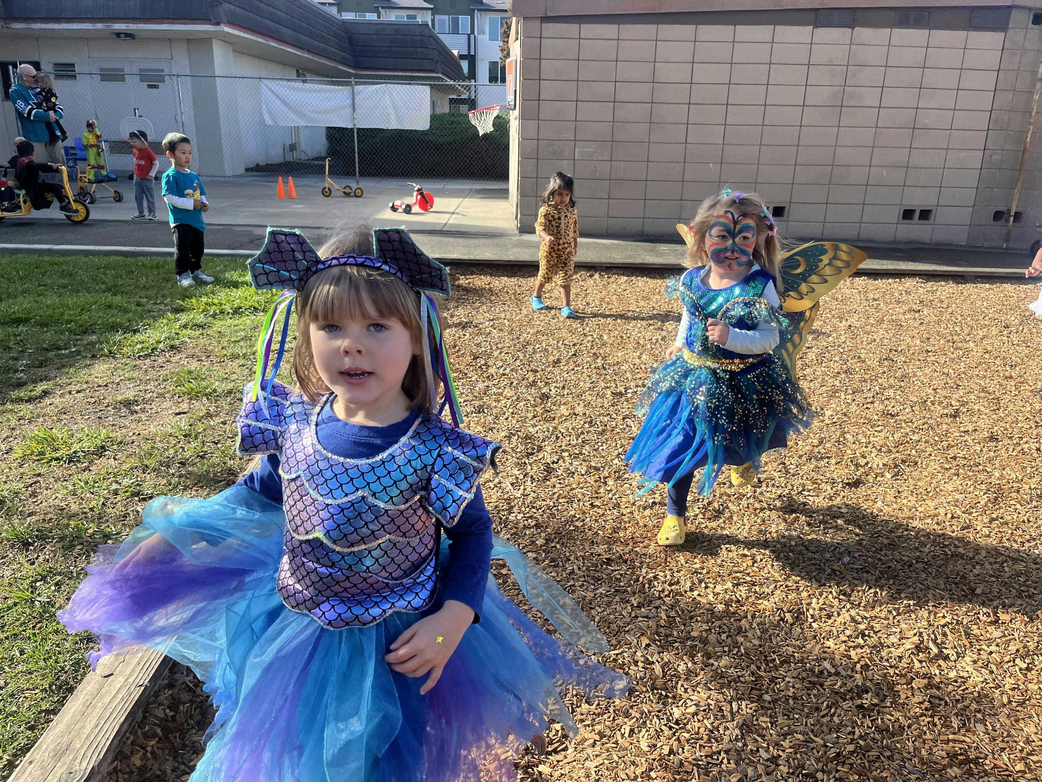 Child in blue costume with other children in costumes on playground