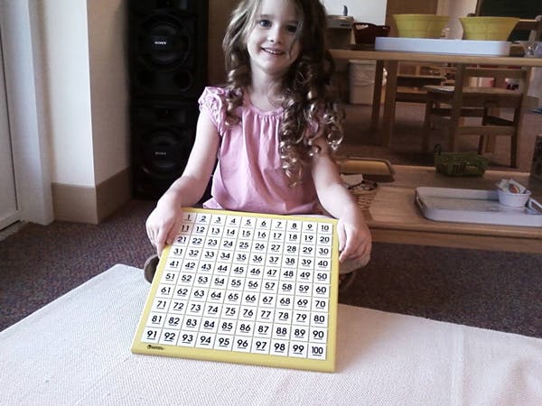 Child holding a 100-number chart
