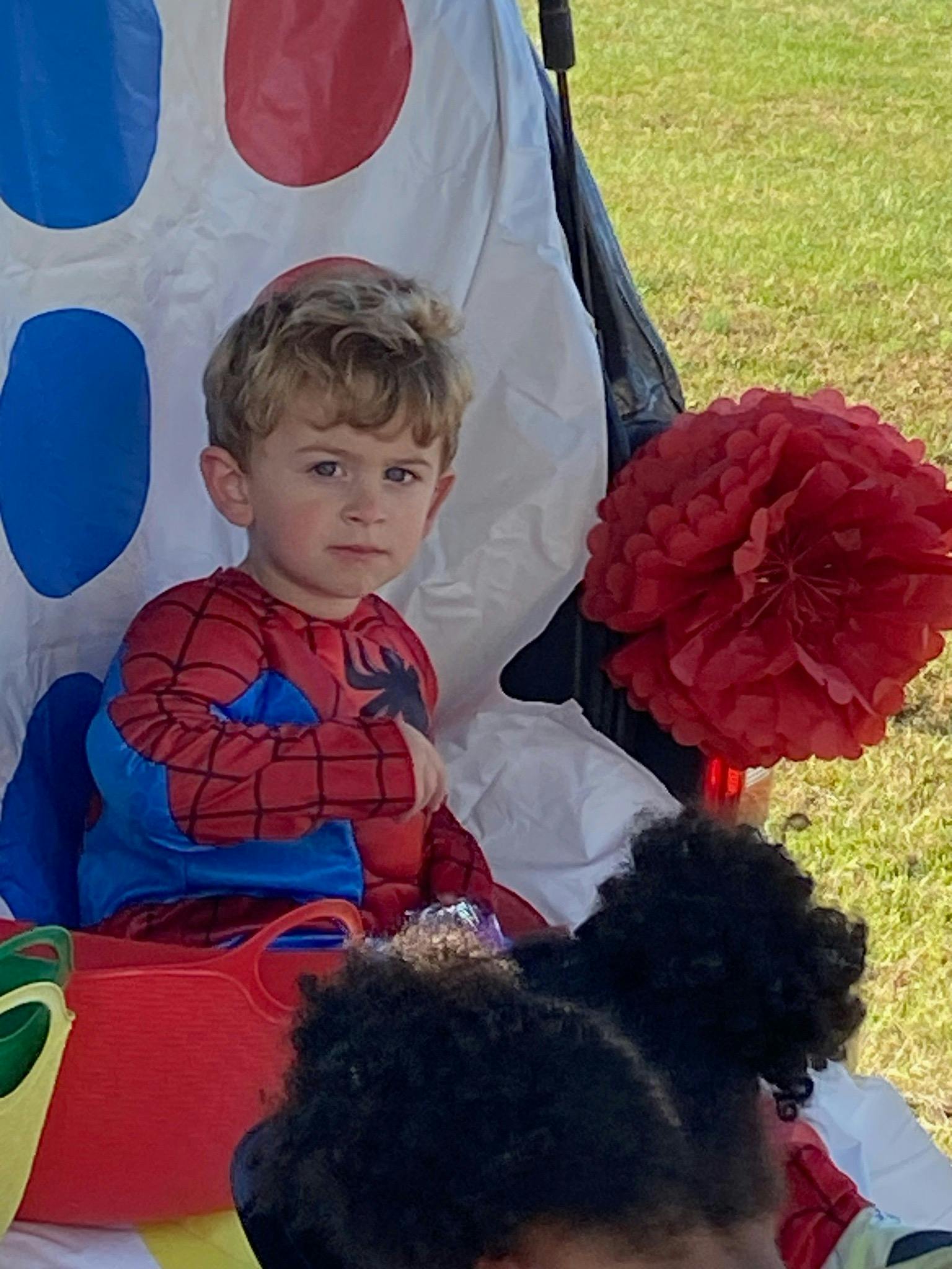 Child in a Spider-Man costume sitting outdoors