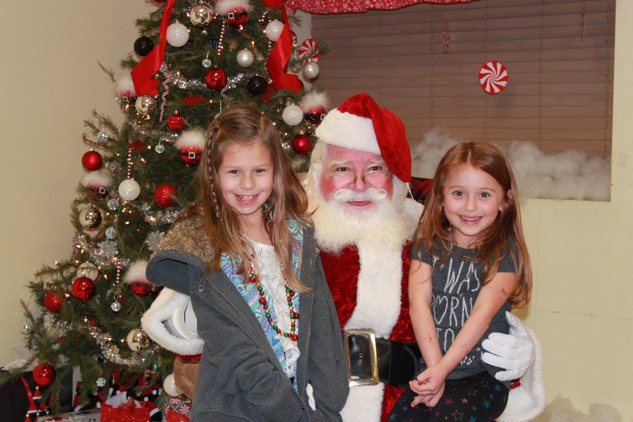 Santa Claus with two children in front of a Christmas tree