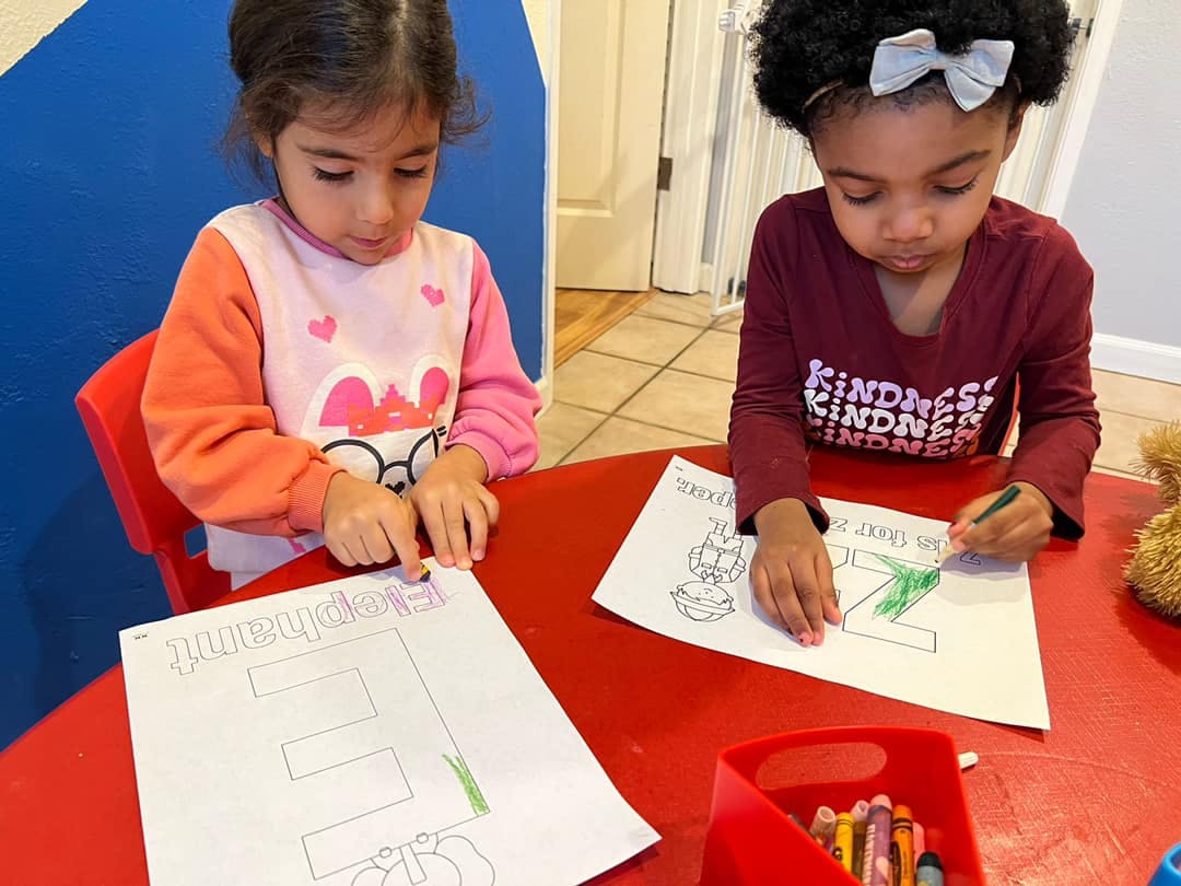 Two children coloring at a red table