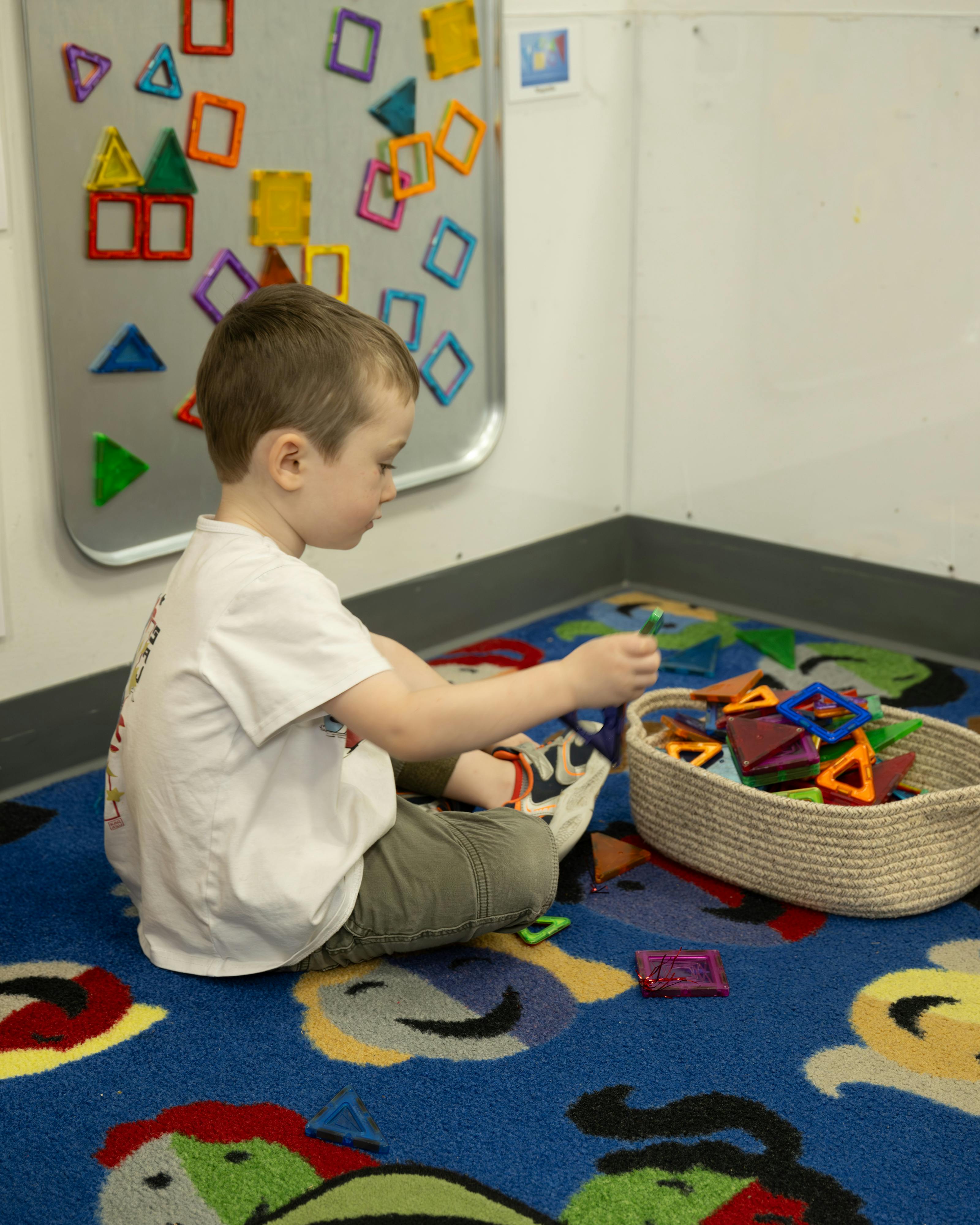 Child sitting on a rug playing with magnetic shapes