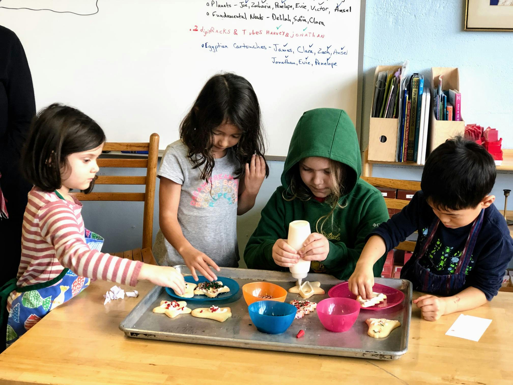 Four children decorating cookies at a table