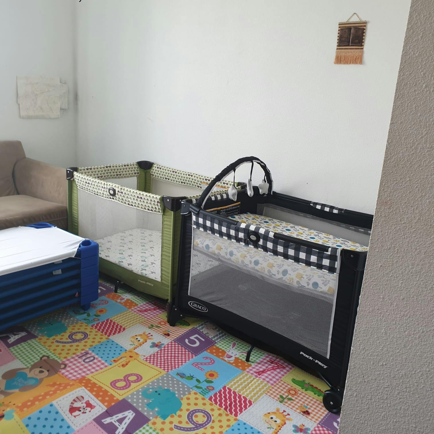 Two portable cribs on a colorful alphabet playmat