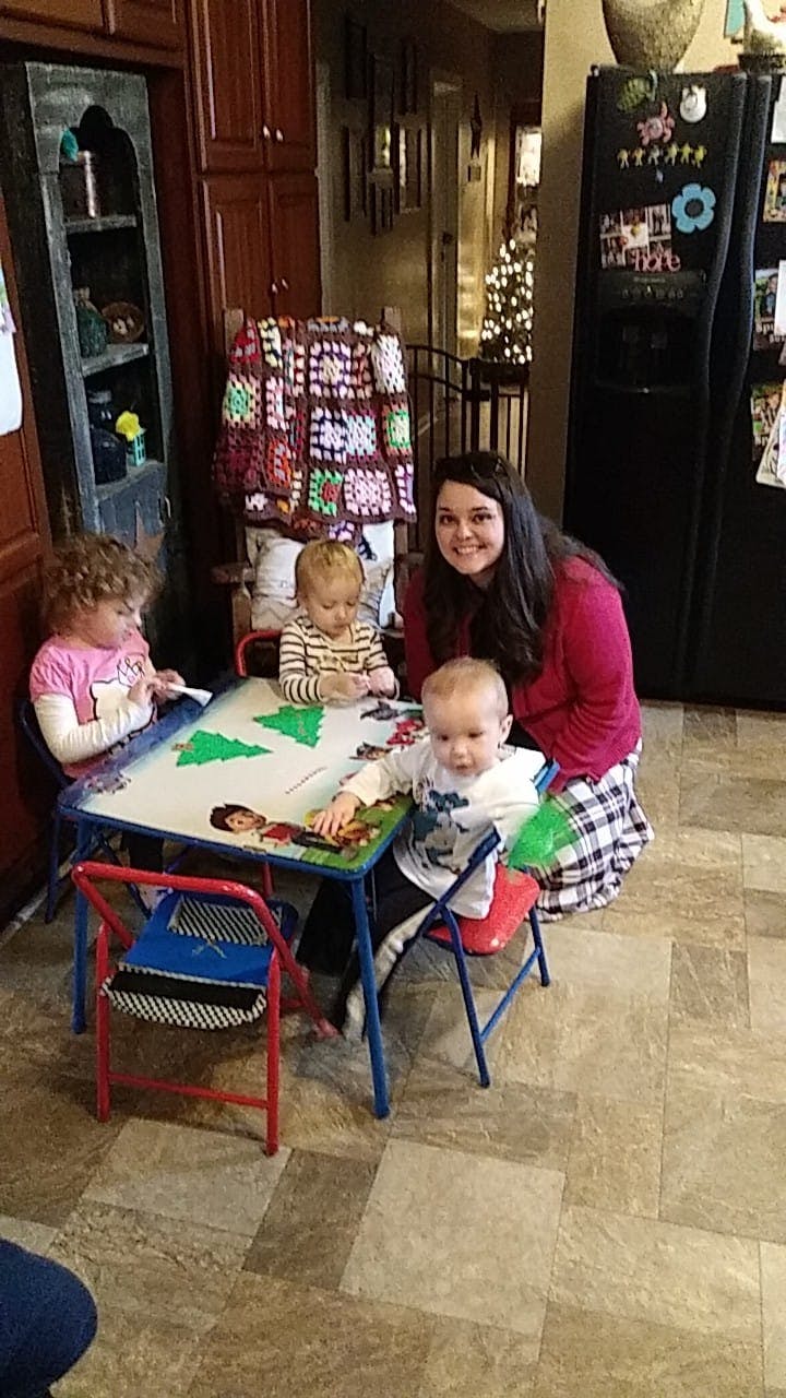 Person with three children at a small table