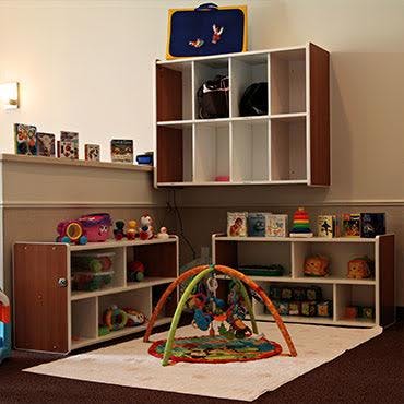 Playroom with shelves of toys and a baby play mat