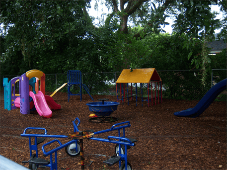 Playground with colorful slides, a blue merry-go-round, and a playhouse