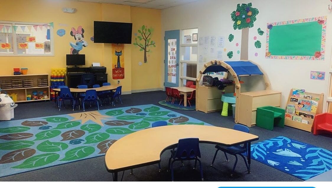 An empty classroom with small tables and chairs for children