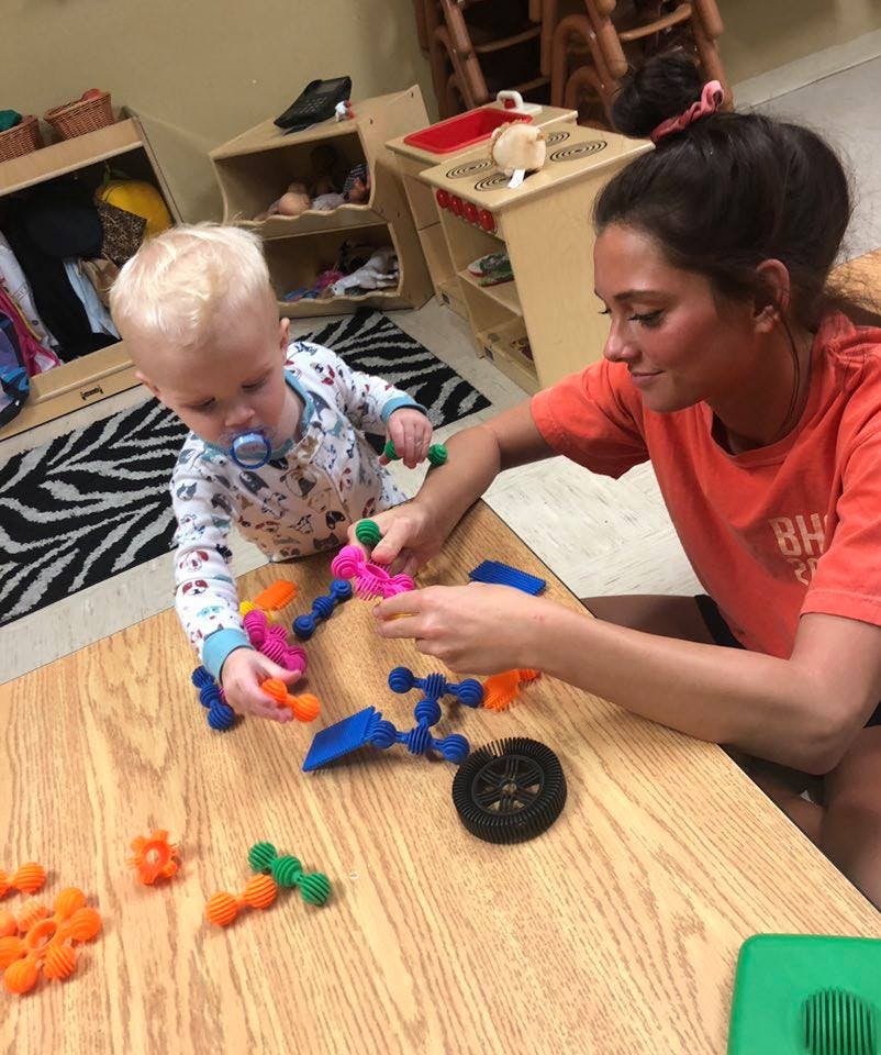 Person and child playing with colorful building toys on a table