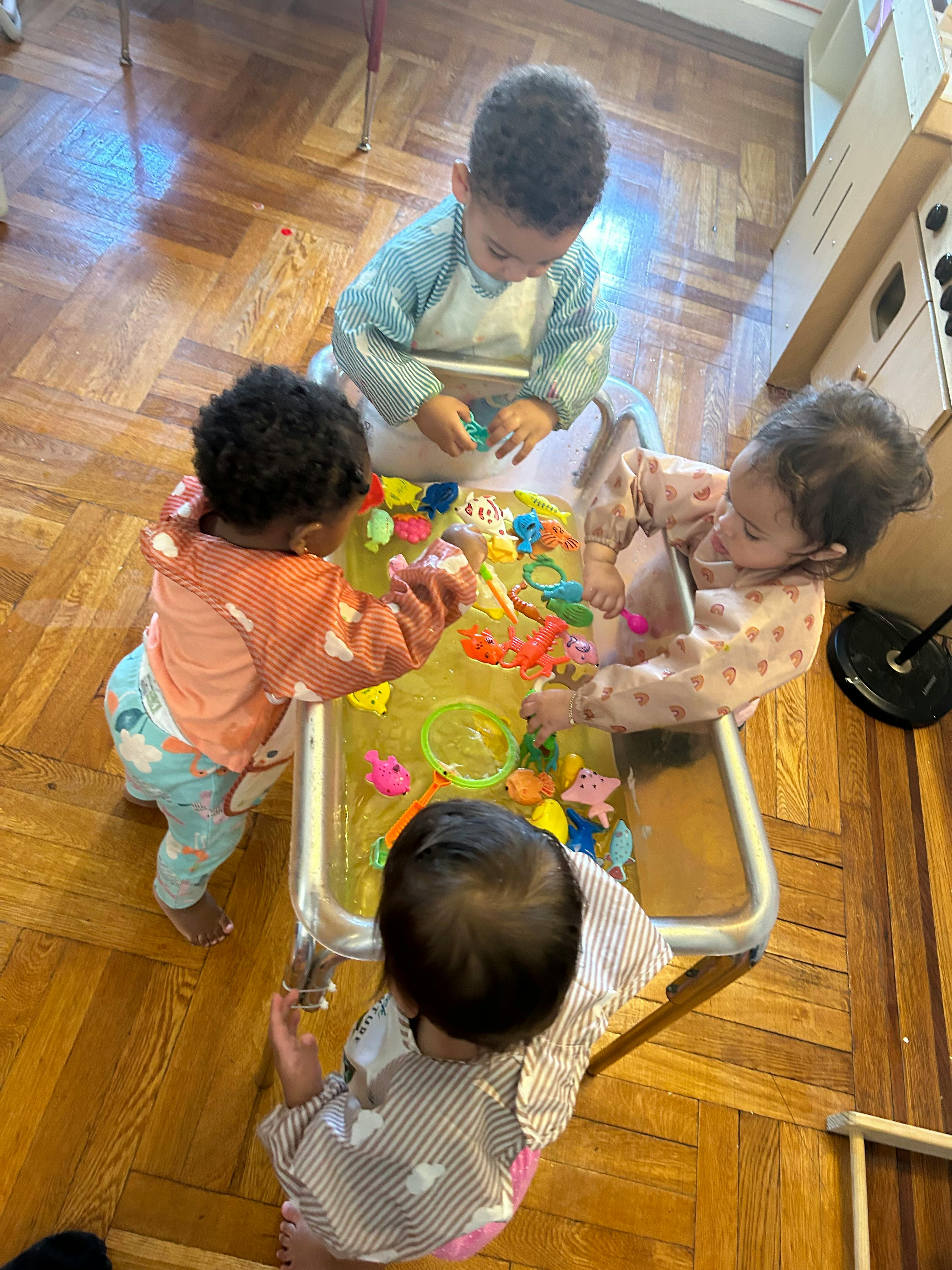Four children playing with toys in a water table
