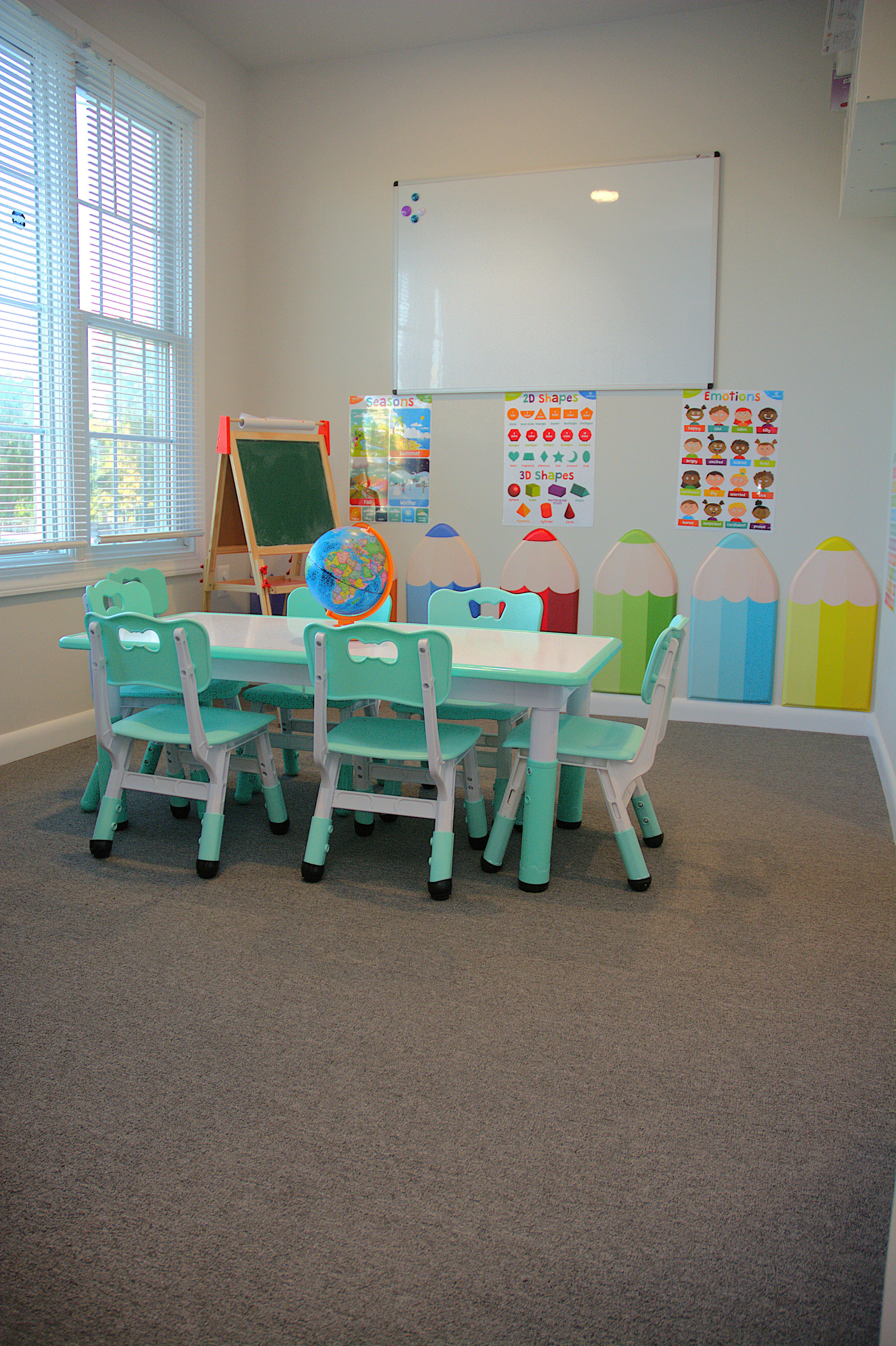 Classroom with small tables and chairs, whiteboard, and educational posters