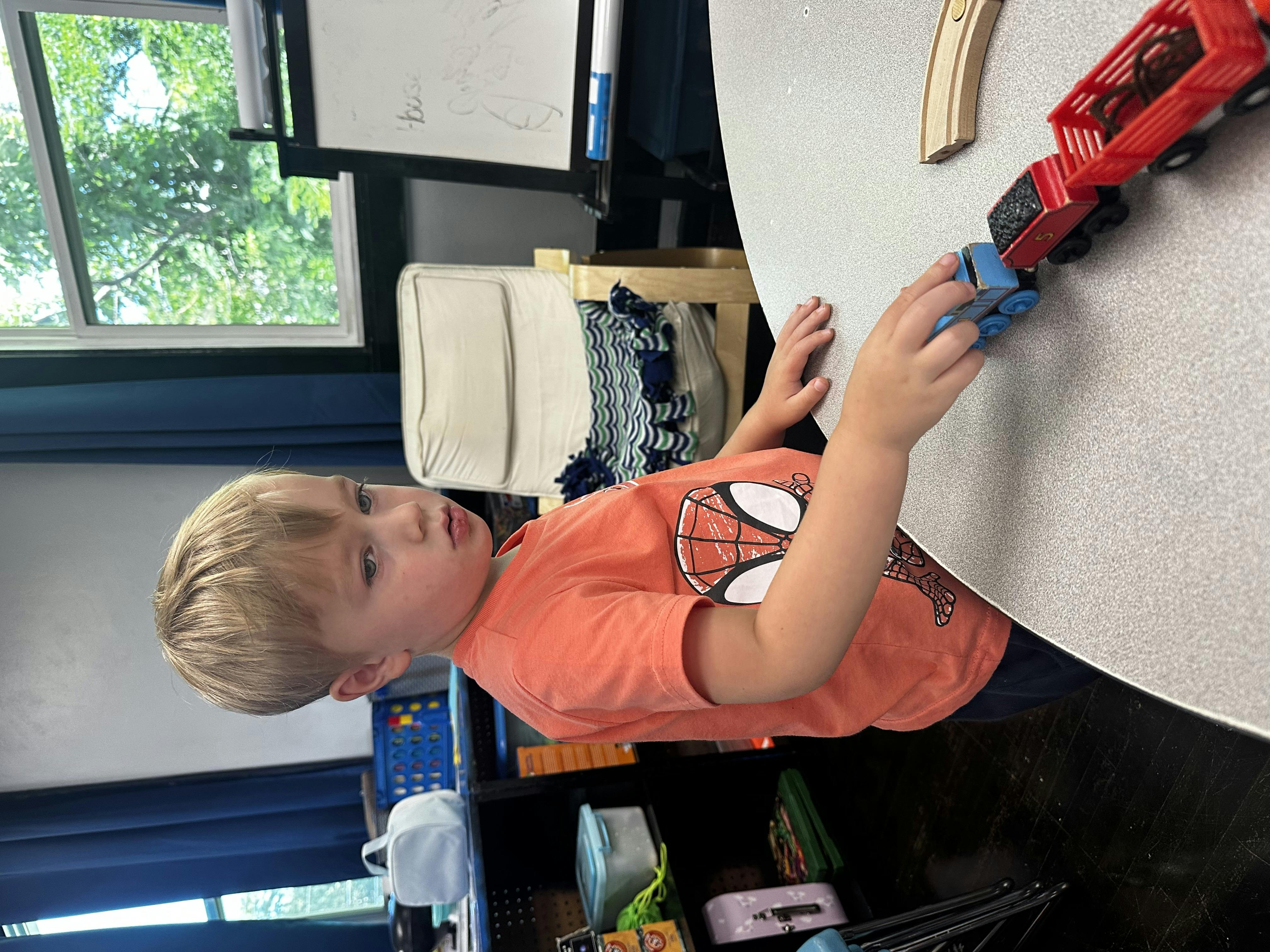 Child playing with a toy train on a table