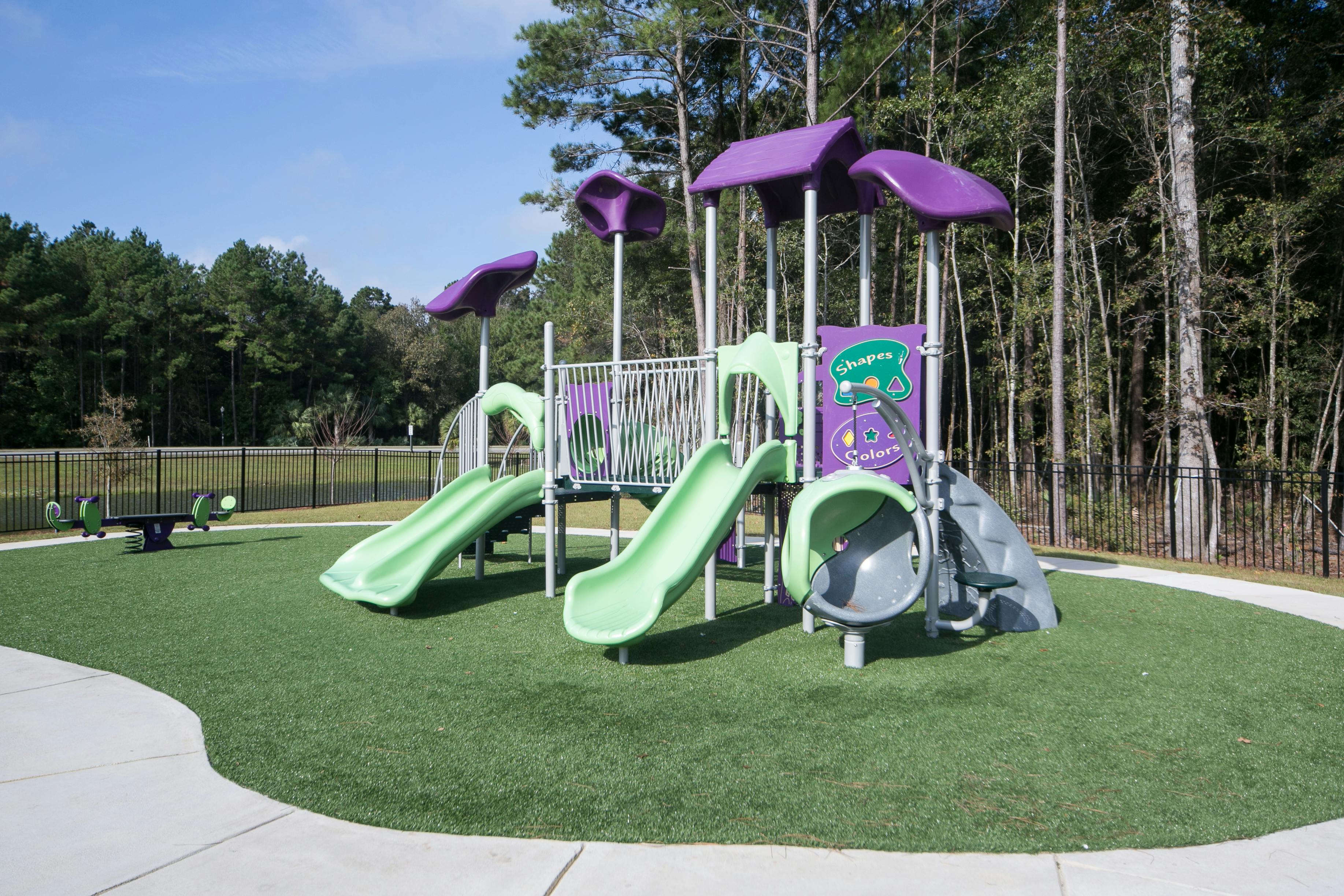 Playground with green slides and purple structures on artificial turf
