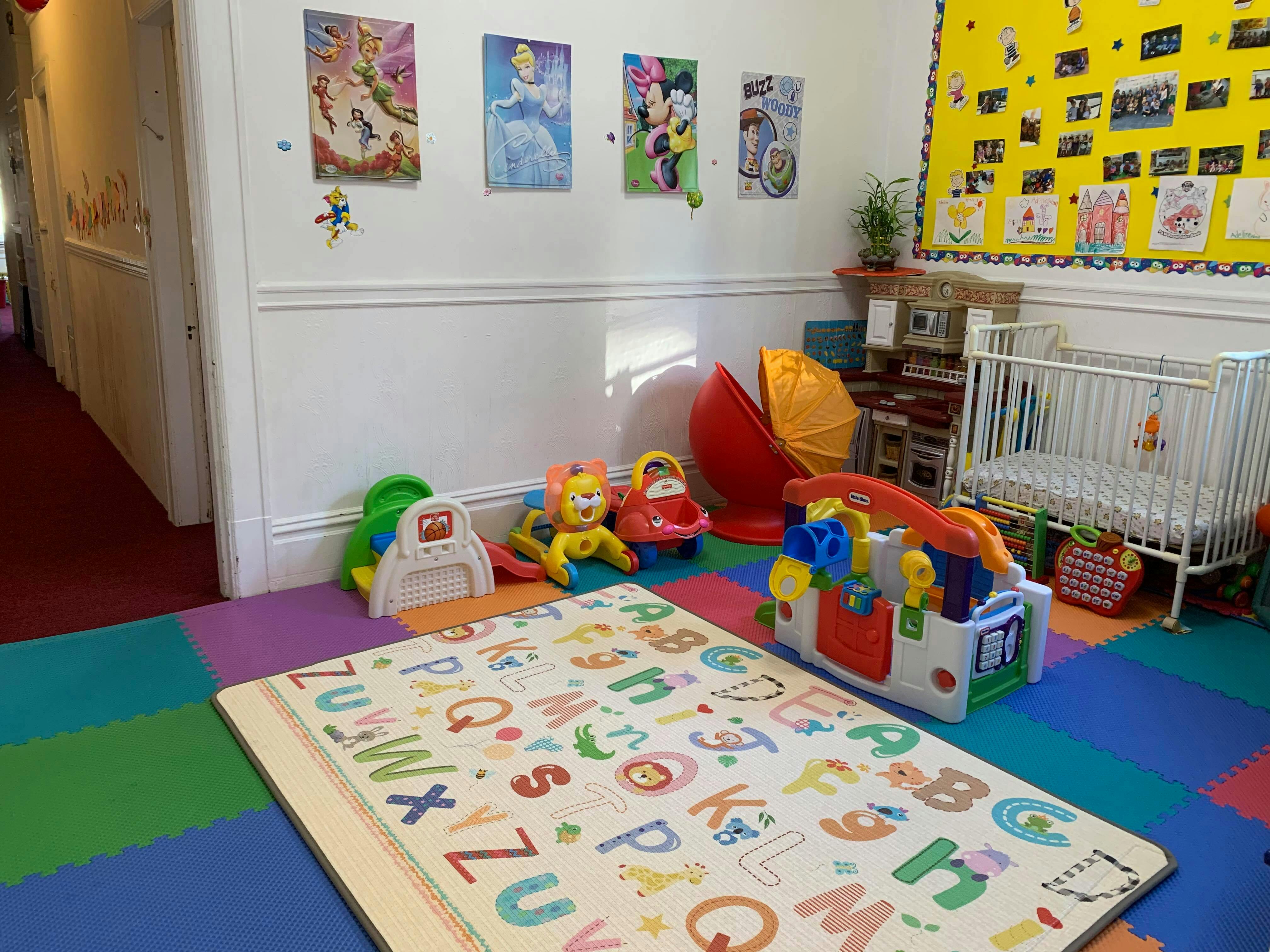 Playroom with alphabet mat, toys, and a crib