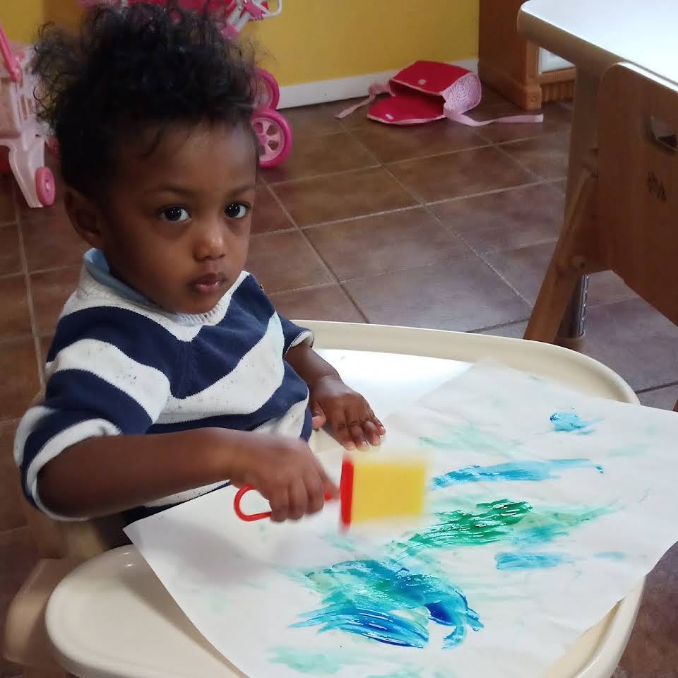 Child painting with a sponge on paper