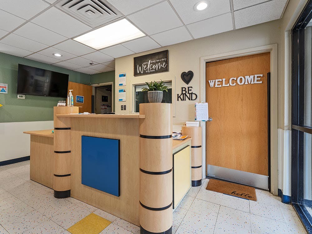 Reception desk with a welcome sign on a door and "Be Kind" art