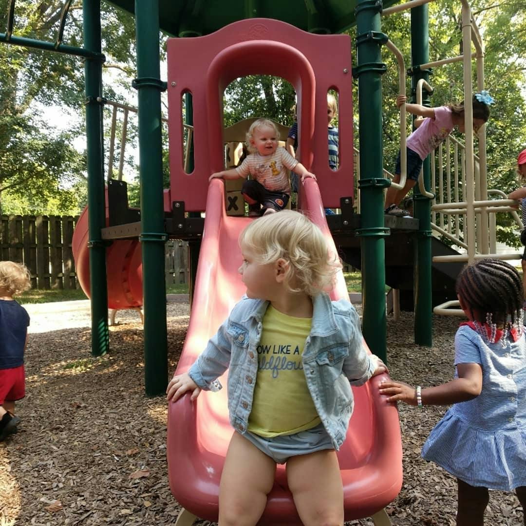 Children playing on a red slide and playground equipment