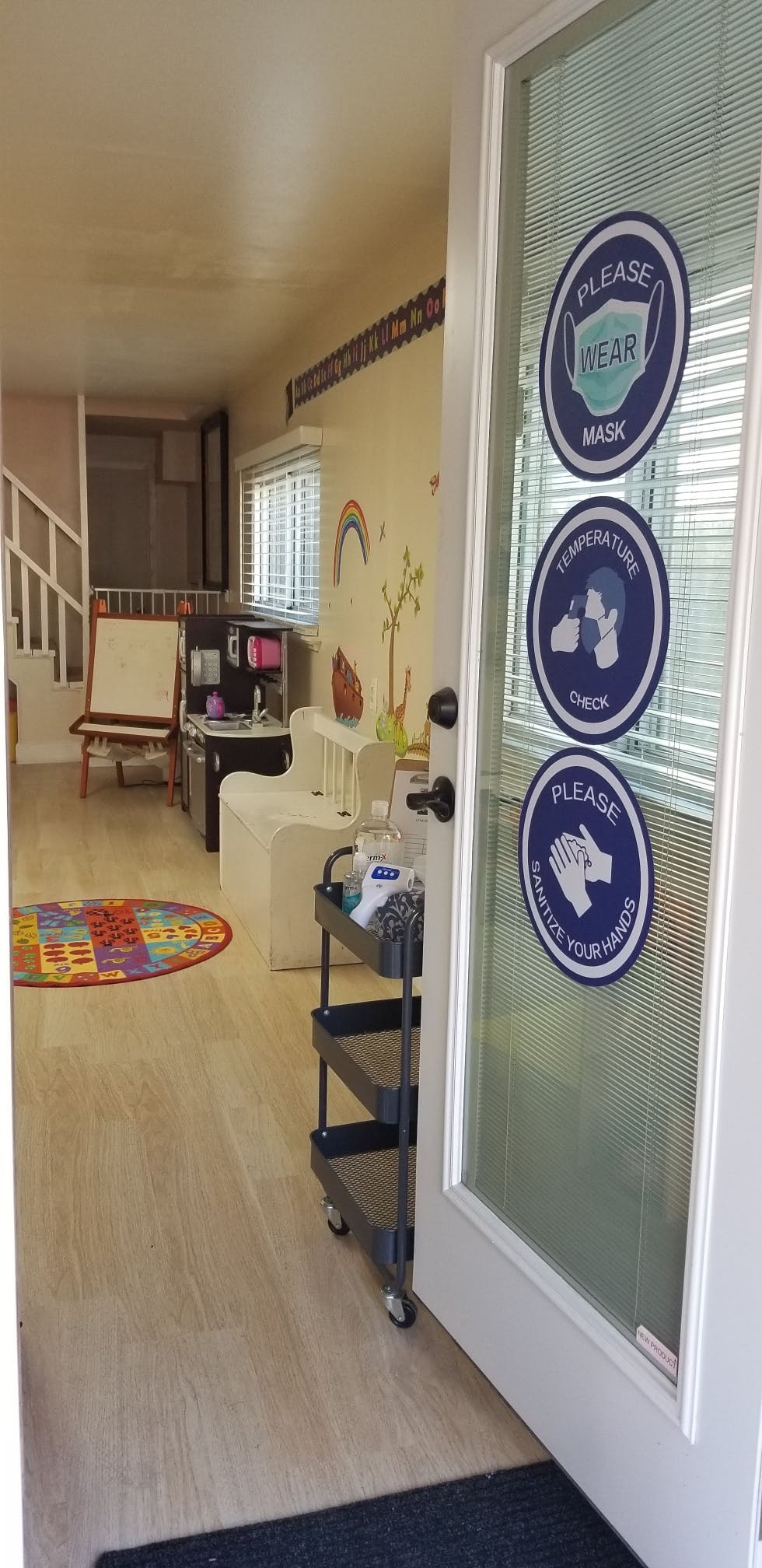 Open door with signs for mask, temperature check, and hand sanitizing