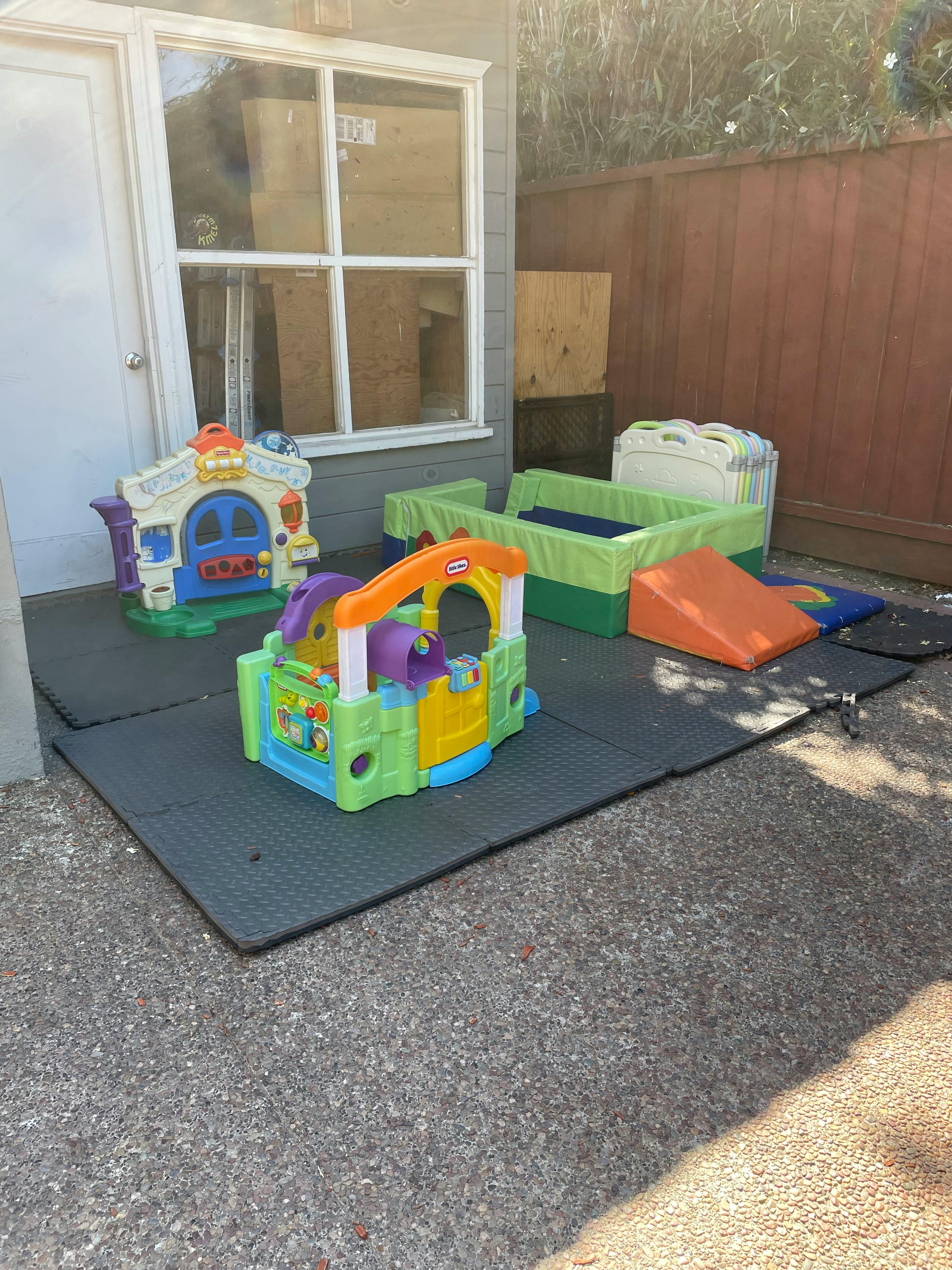 Outdoor play area with colorful plastic toys on black mats