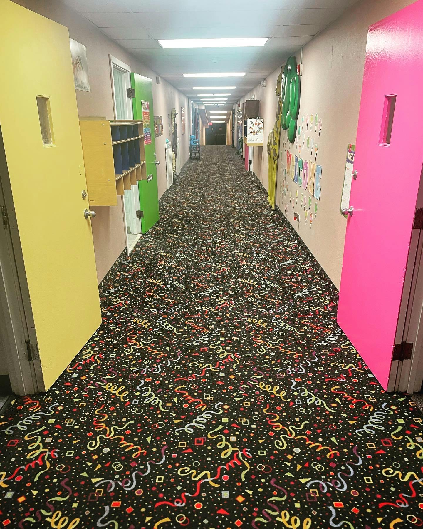 Long hallway with colorful doors and patterned carpet