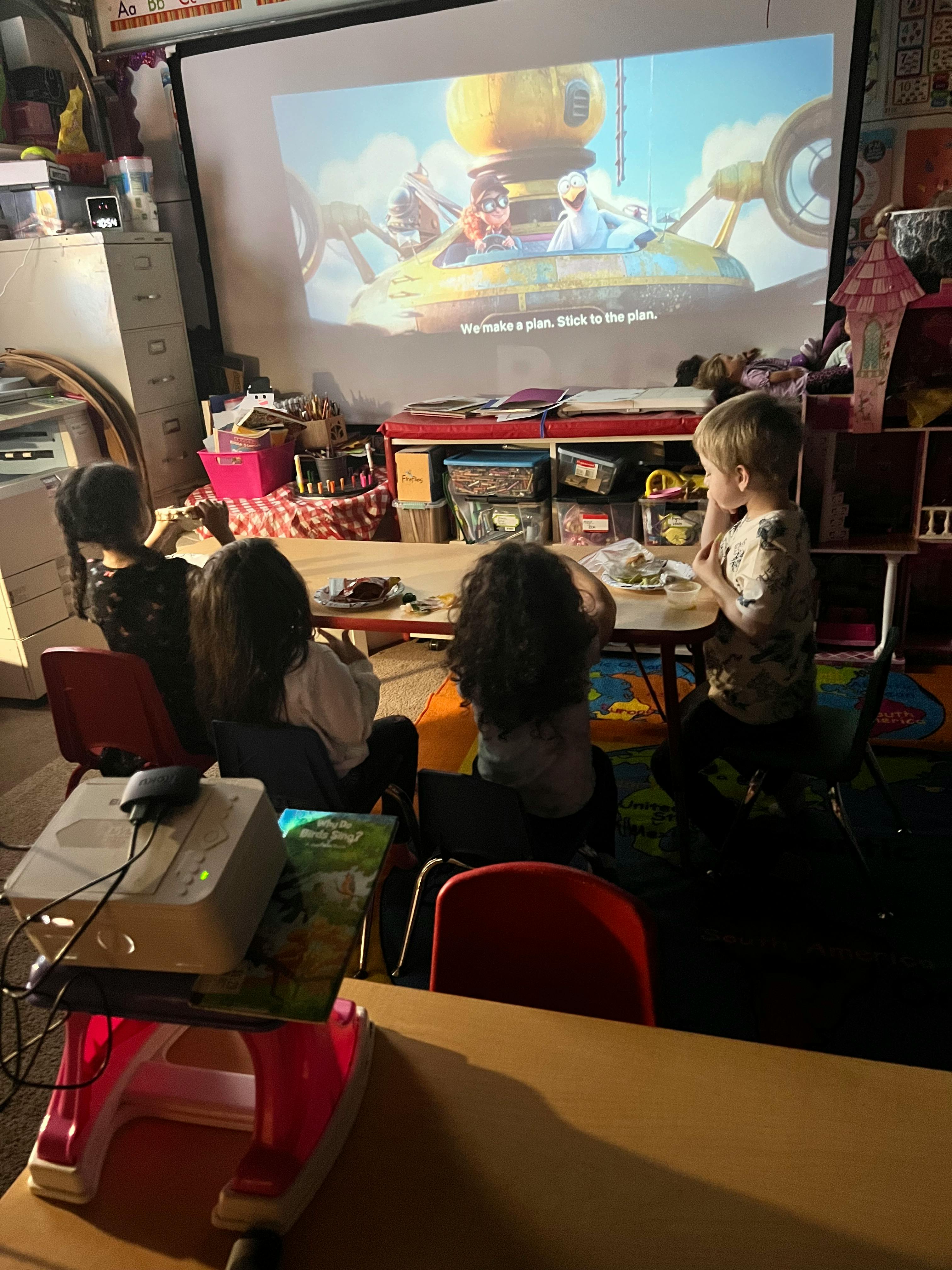 Children watching a movie projected onto a screen in a classroom