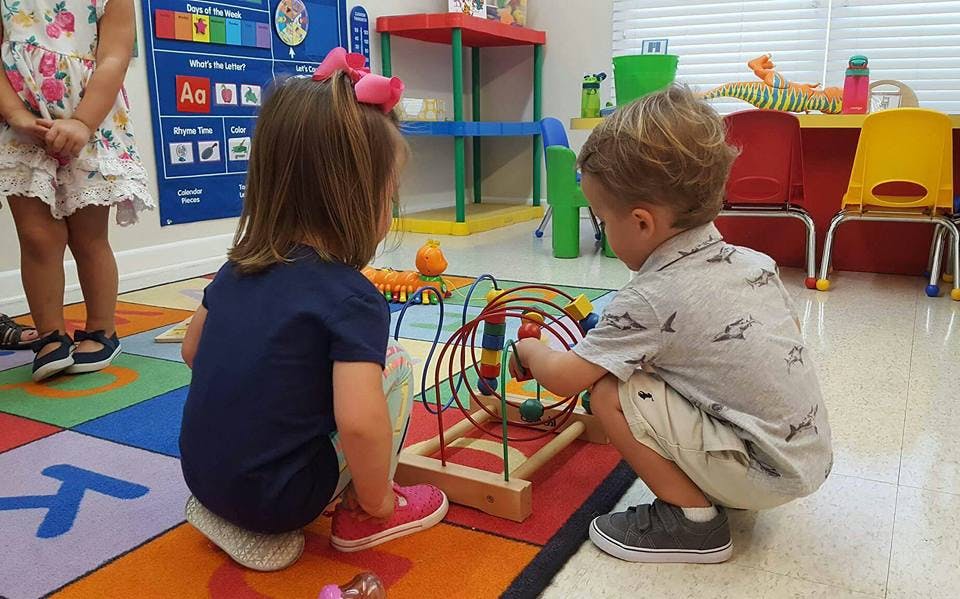 Two children playing with a bead maze toy