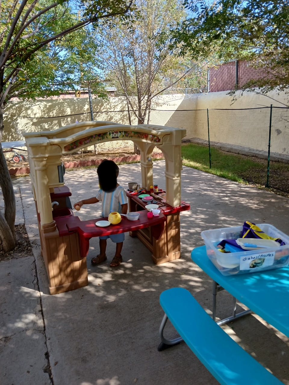 Child playing at an outdoor play kitchen
