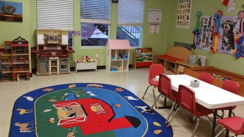 Playroom with a rug, toy kitchen, dollhouse, and small table with chairs