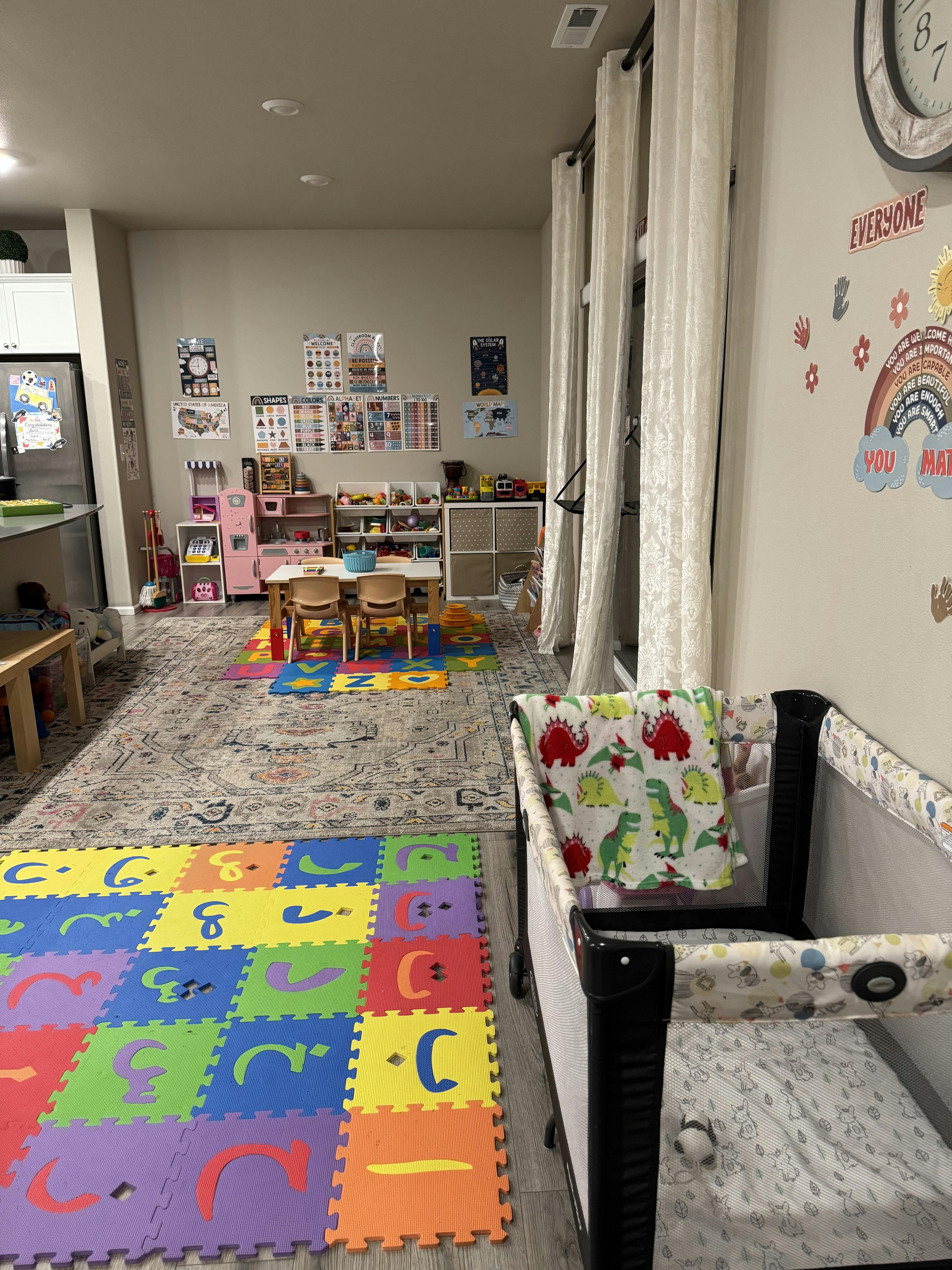 Playroom with colorful floor mats, small table and chairs, and a crib