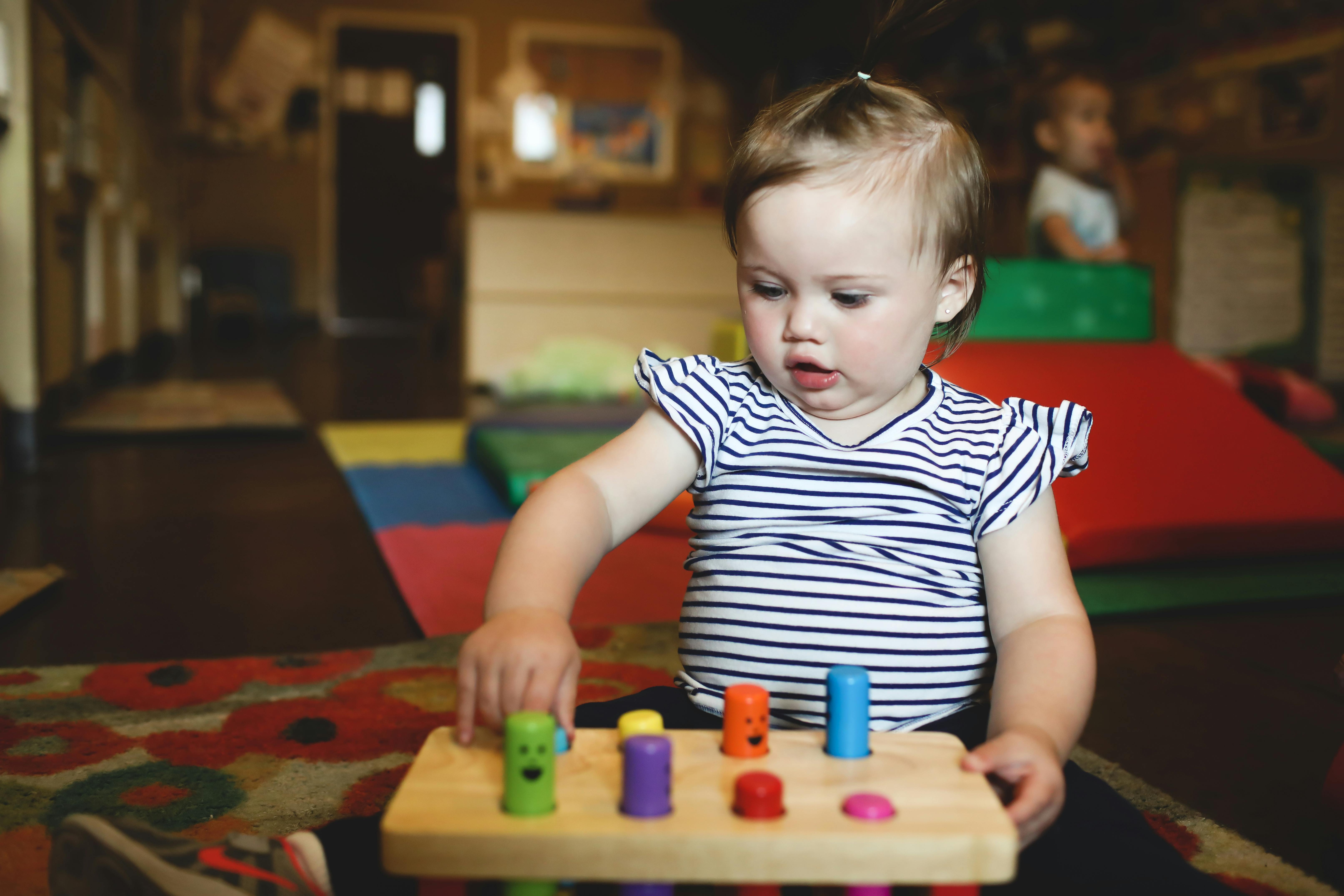 Child playing with a wooden shape sorter toy
